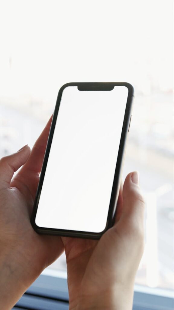 A close-up shot of hands holding a smartphone with a blank screen for mockup usage.